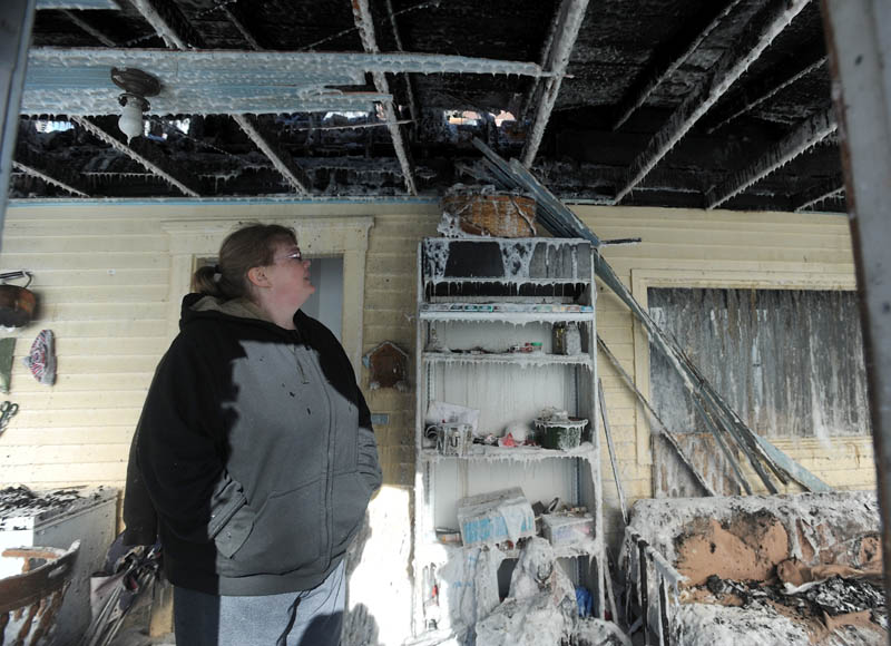 Becky Williams, 40, walks through the iced-over entry way of her Madison Avenue home in Madison after it was destroyed by fire around 3 am Friday. Six area fire departments responded to the blaze, as temperatures reached below zero degrees.