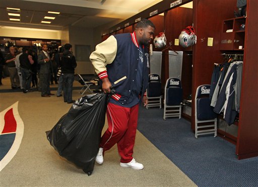 New England Patriots defensive tackle Brandon Deaderick carries a trash bag of his belongs through the locker room at Gillette Stadium in Foxborough, Mass., on Monday.