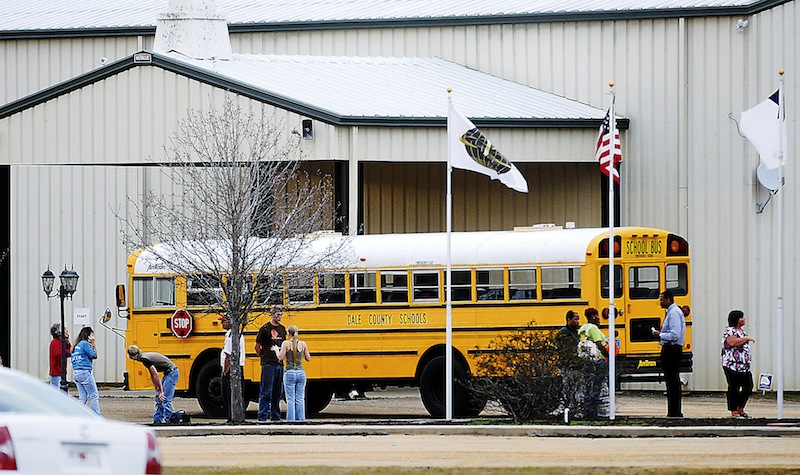 In this Tuesday, Jan 29, 2013 photo, residents look over the school bus where a shooting occurred near Destiny Church along U.S. 231, just north of Midland City, Ala. on Tuesday. Police, SWAT teams and negotiators were at a rural property where a man was believed to be holed up in a homemade bunker Wednesday, HAN 30, 2013 after fatally shooting the driver of a school bus and fleeing with a 6-year-old child passenger, authorities said. The man boarded the stopped school bus in the town of Midland City on Tuesday afternoon and shot the driver when he refused to let the child off the bus. The bus driver died. (AP Photo/The Dothan Eagle, Danny Tindell)