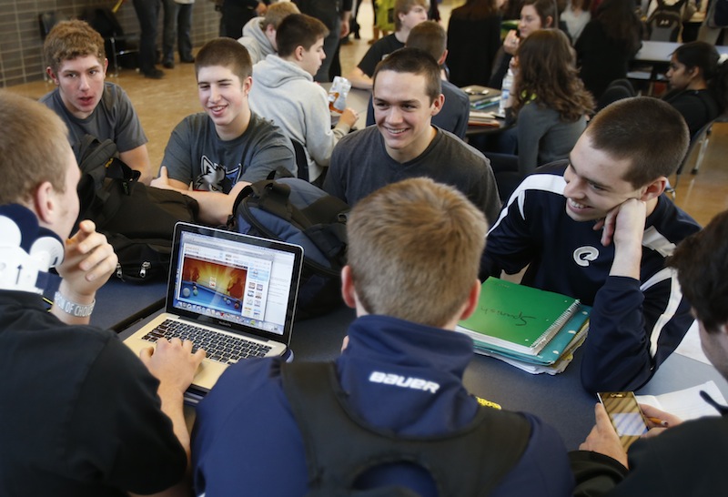 In this Jan. 18, 2013 photo, Chanhassen High School students relax while another plays a computer game during a 20-minute "recess" in the cafeteria commons area during a stress break Jan. 18, 2013 in Chanhassen, Minn. Chanhassen is among a small but growing number of schools that has homework-free nights scattered throughout the school year along with the "recess" breaks two days a week where students chat, catch up on homework, rest, play games like hackie sack or grab a snack. (AP Photo/Jim Mone)