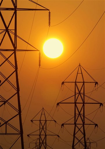 In this Sepember 2003 file photo, the setting sun silhouettes electric transmission lines. New England's power grid operator says wholesale electricity prices dropped by nearly 23 percent regionally last year thanks to falling natural gas prices and decreased demand. (AP Photo/Mark Duncan, File)
