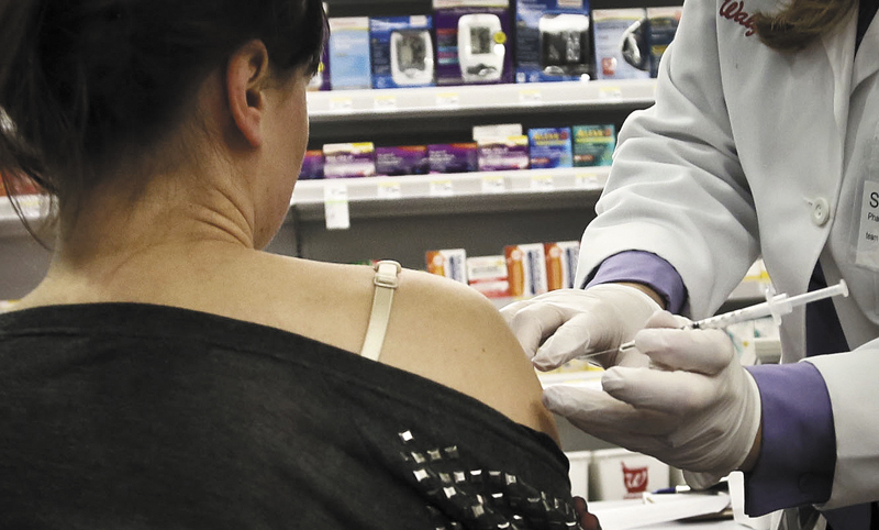 Pharmacist Stacia Woodcock, a pharmacy manager for Walgreens in New York City, administer a flu vaccine on Jan. 14. Early signs indicate the influenza pandemic in Maine is easing, according to state health officials.