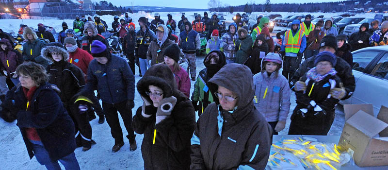 People gather and try to stay warm during a prayer during the Torch Light Snowmobile Safety Vigil in Rangeley Friday night.