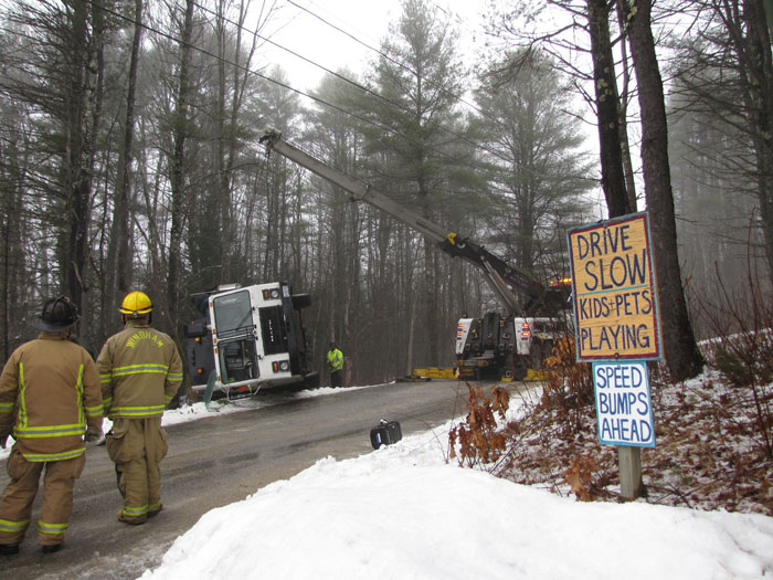 Rescue personnel watch as a tow crane begins to lift a Pine Tree Waste truck that rolled over in Windham on Wednesday morning. Contributed photo by Elizabeth Nangle.