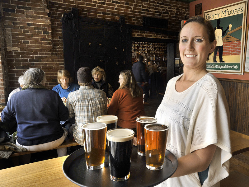 Rhea Schneider, a server at Gritty McDuff’s in Portland, with a tray filled with pints of the popular brew pub’s signature ales.