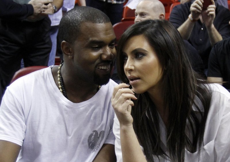Kanye West, left, talks to Kim Kardashian before an NBA basketball game between the Miami Heat and the New York Knicks on Dec. 6 in Miami.