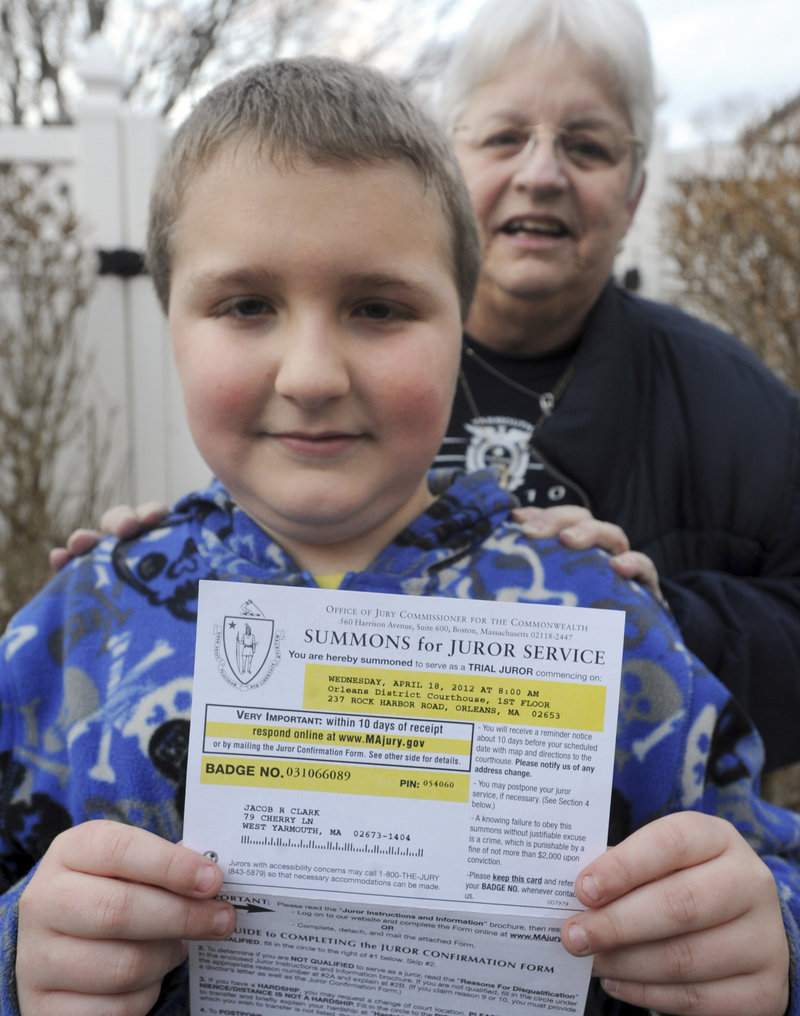 Jacob Clark, 9, displays the notice he received to appear for jury duty in South Yarmouth, Mass., in March. His grandmother Deborah Clark stands behind him. Documents mistakenly listed 1982 for his birth year instead of 2002.