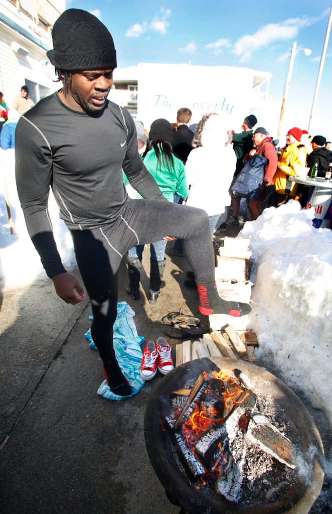 Edwin James of Killeen, Texas, warms his feet by the fire at The Brunswick after taking the plunge during the Lobster Dip to benefit Special Olympics Maine on Tuesday.
