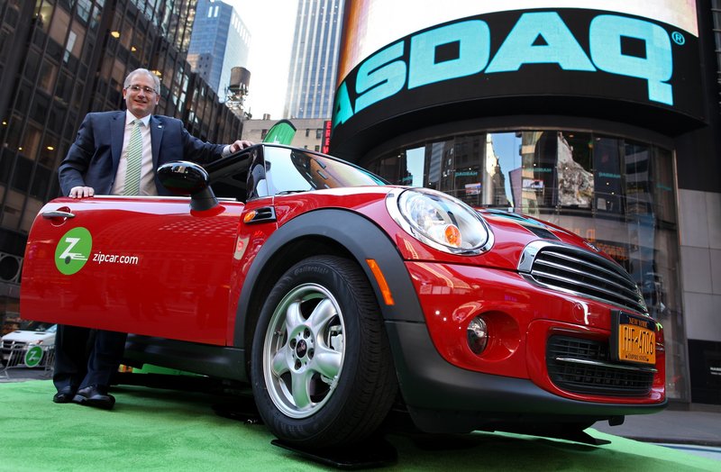 Zipcar Chairman and CEO Scott Griffith stands with a Zipcar Mini-Cooper before the opening bell outside the NASDAQ market site in New York. Avis is buying Zipcar for $491.2 million, expanding its offerings to hourly rentals.