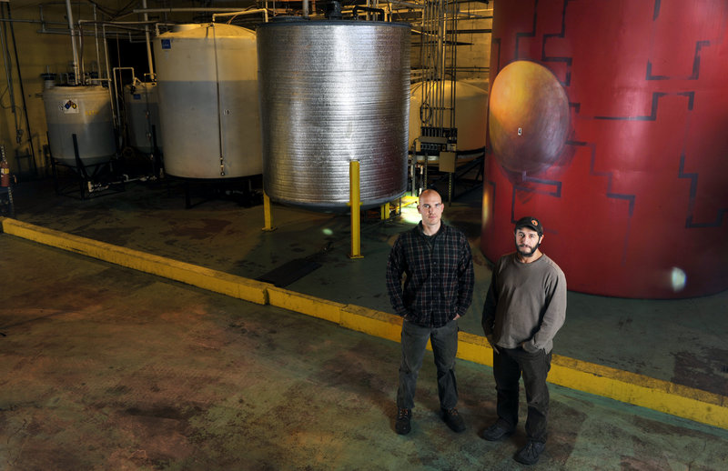 Matt Pemberton, left, of Maine Standard Biofuels and founder Jarmin Kaltsas stand near the company’s colorful holding tanks. Its Portland plant now produces 300,000 gallons a year, but is capable of 1.5 million gallons.