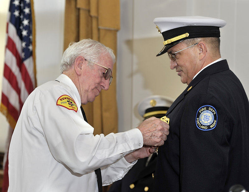 Jerome LaMoria, right, Portland’s new fire chief, has his chief’s badge pinned on him by his father, Norman – a former fire chief in Vermont – during the swearing-in ceremony at City Hall on Thursday.