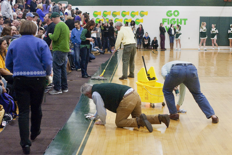 Paul Pendleton, left, vice principal of McAuley High, and athletic director Joseph Kilmartin unsuccessfully try to dry the floor during one of the interruptions of the game between McAuley and Deering.