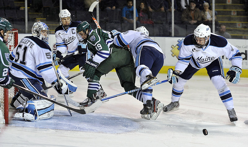 Maine goalie Martin Ouellette keeps his eye on the loose puck as Mercyhurst’s Matthew Zay (19) is knocked out of the play by Maine’s Joey Diamond during a 2-1 win by the Black Bears at the Cumberland County Civic Center on Friday night.