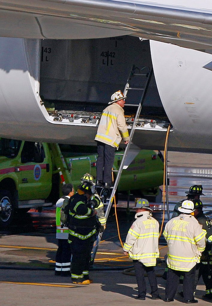 Boston firefighters examine the cargo hold of a Japanese airliner that sustained a small electrical fire following a flight from Tokyo to Logan International Airport on Monday.