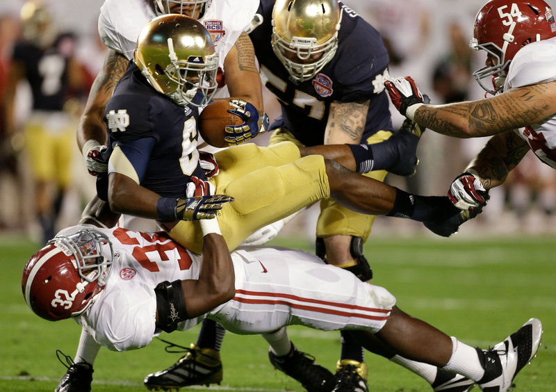 C.J. Mosley, 32, of Alabama takes down Notre Dame’s Theo Riddick in the first half of Monday night’s BCS championship game in Miami. The Crimson Tide won their second straight BCS title and third in four years, 42-14.