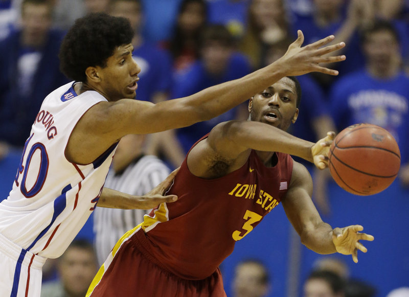 Melvin Ejim of Iowa State makes a pass while covered by Kansas’ Kevin Young in Wednesday night’s game at Lawrence, Kan. The Jayhawks won in overtime, 97-89.