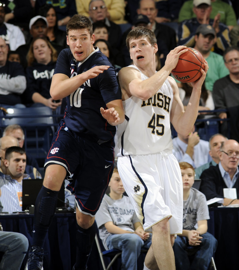Notre Dame’s Jack Cooley grabs a rebound away from Connecticut’s Tyler Olander during Saturday’s game at South Bend, Ind. UConn upset the 17th-ranked Fighting Irish, 65-58.