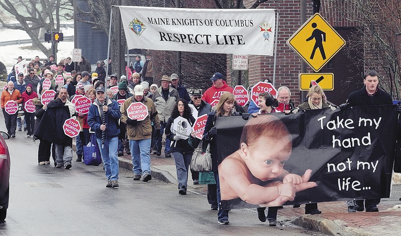 Anti-abortion protesters cross Capitol Street as they march from the St. Michael School gymnasium to the State House during a Hands Around the Capitol event Saturday in Augusta.