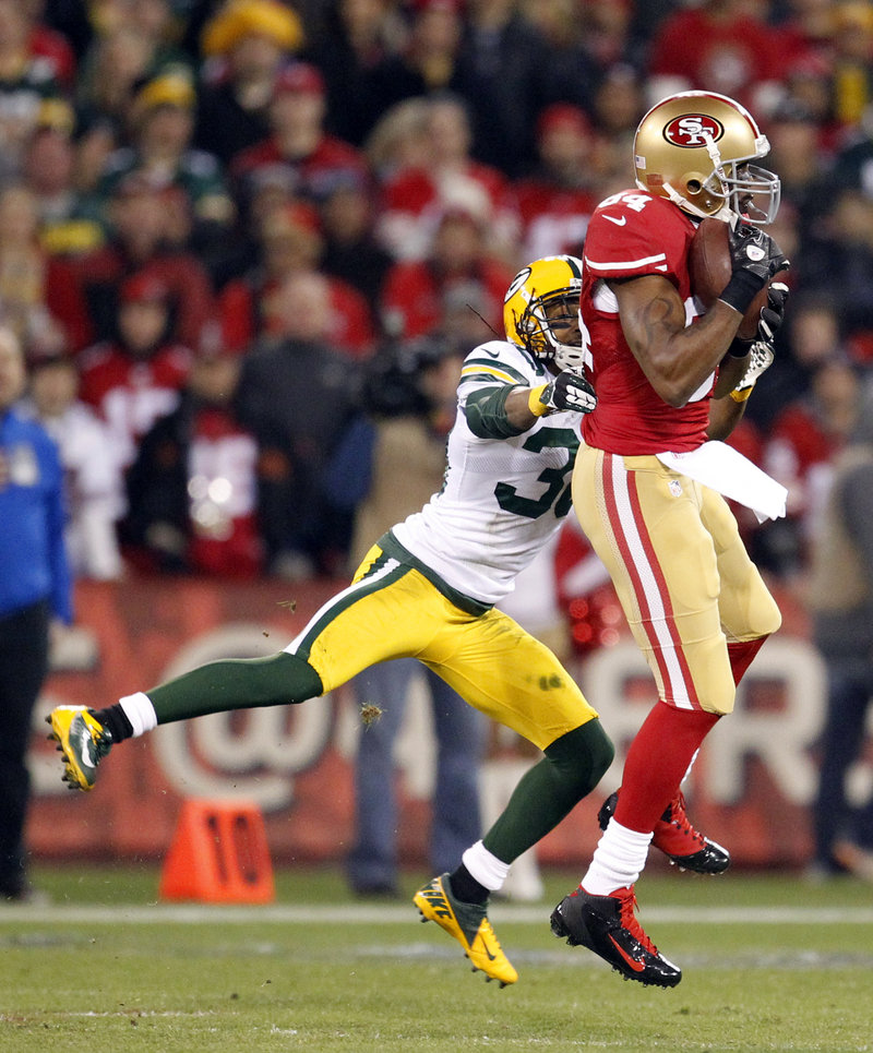 Randy Moss, now a role player with the San Francisco 49ers, snags a pass against Green Bay Packers cornerback Tramon Williams in the first half.