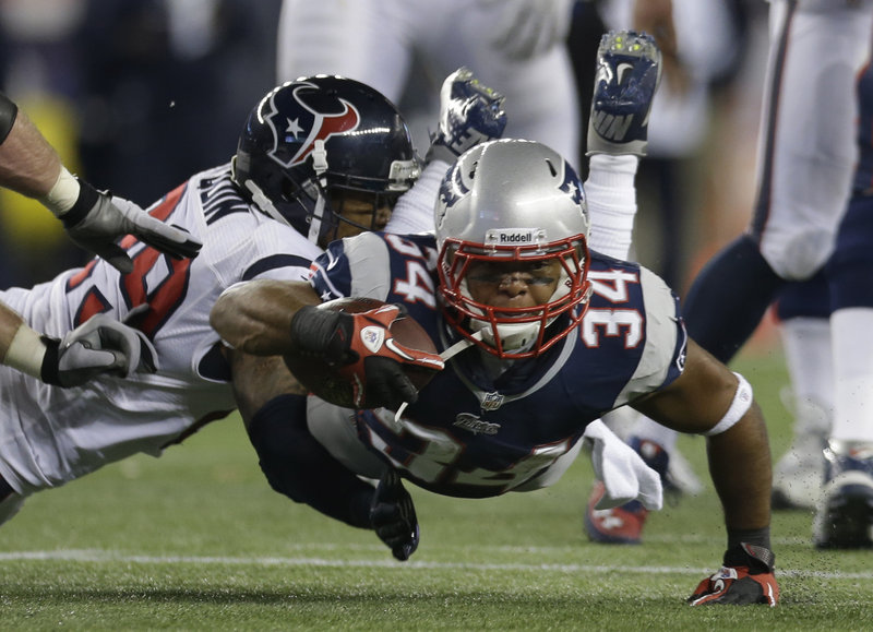 Shane Vereen stretches for extra yardage while being tackled by Houston’s Glover Quin. Vereen scored three touchdowns for the Patriots.