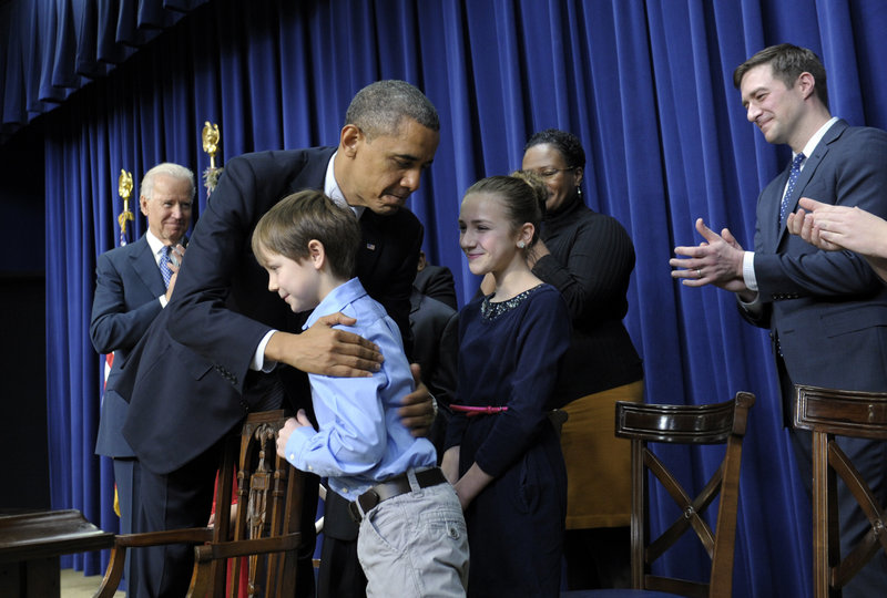 President Barack Obama, accompanied by Vice President Joe Biden, left, hugs 8-year-old letter writer Grant Fritz during a Wednesday news conference on proposals to reduce gun violence at the White House.