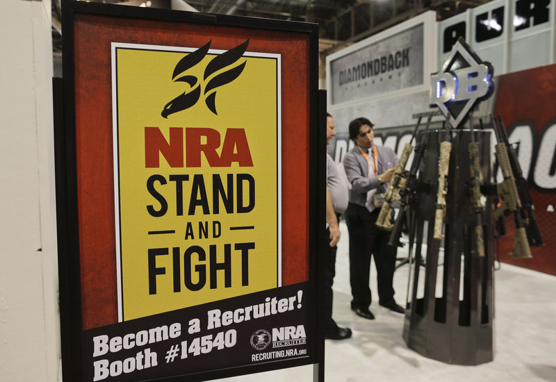 A National Rifle Association poster decorates a booth at the 35th annual "SHOT show" on Wednesday in Las Vegas. Lawmakers both fear and admire the group’s political power.