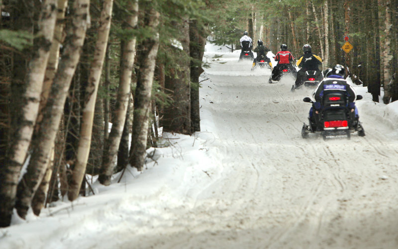 Snowmobilers ride along ITS 84 in Oquossoc on Jan. 12.