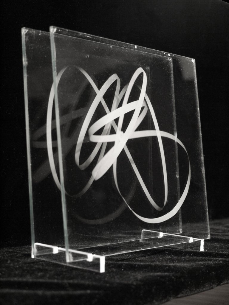 “itiswhatitis” features two series of works by Michael Kolster, including one involving glass plates and swirls of ribbon.