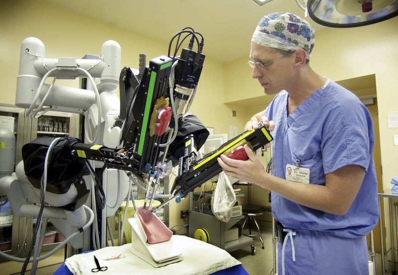 Dr. Moritz Hansen adjusts a surgical robot’s arms before a Maine Medical Center demonstration in 2004. A proposed settlement would give Maine’s 39 hospitals “the cash flow they need to make needed investments in their institutions,” says the president of the Maine Hospital Association.