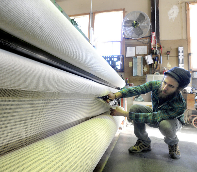 Ryan Benoit cuts a roll of fabric from a loom at the Brahms Mount blanket factory.