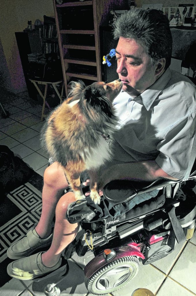 David Aldrich, pictured last month in Delray Beach, Fla., uses his mouth to give a biscuit to his dog, Skipper. Aldrich was left a quadriplegic and blind after a fall in 2002.