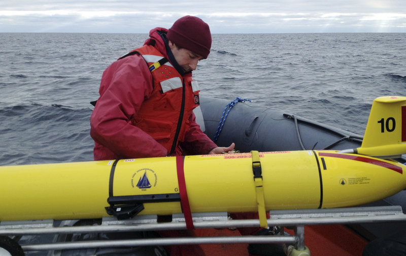 Aboard a ship Dec. 4 in the Gulf of Maine, Mark Baumgartner, a scientist at Woods Hole Oceanographic Institution and project co-leader, secures an underwater robot, or glider, used to collect acoustic data to help scientists locate endangered whales.