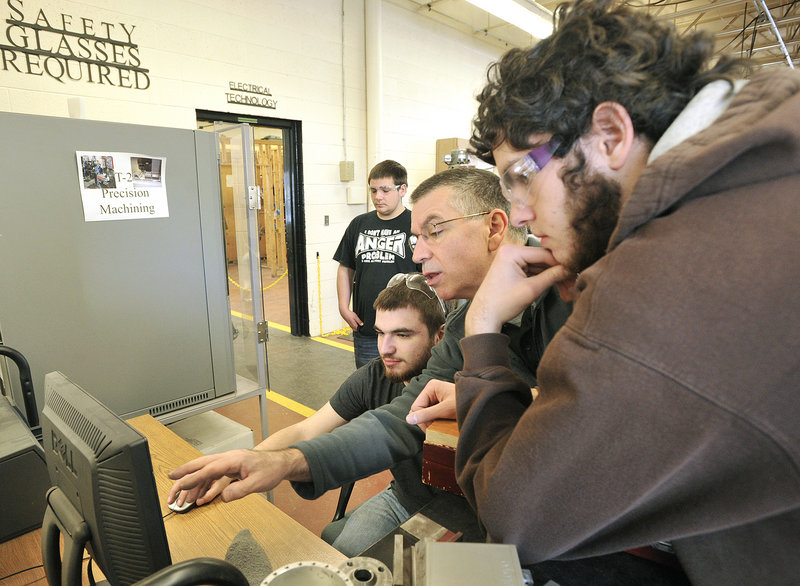 Marc Cadorette, an instructor at the Biddeford Regional Center of Technology, works with students in the machine tool technology class to use a computer program that automates the drilling machine.