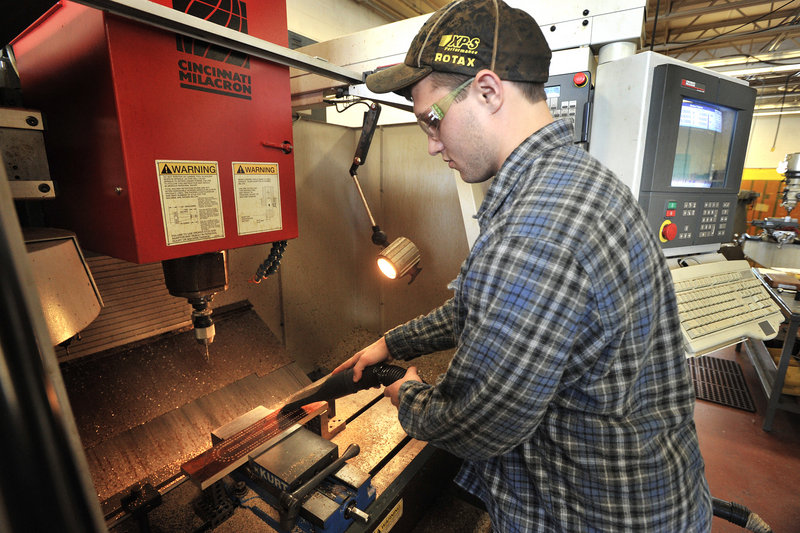 Student Jeremy Lambert vacuums sawdust from a drilled board before removing it from the computerized drill machine.