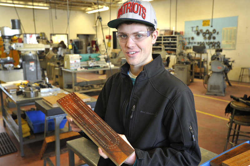 Patrick Wilson, a student at the Biddeford Regional Center of Technology, shows a cribbage board that was drilled by a computerized machine.