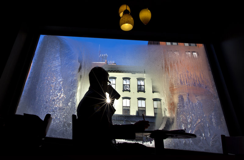 Erin Leighton sips a coffee while seated next to a frost-covered window at a coffee shop, Thursday, Jan. 24, 2013, in Portland, Maine. An arctic cold front with sub-zero temperatures continues to grip the region. (AP Photo/Robert F. Bukaty)