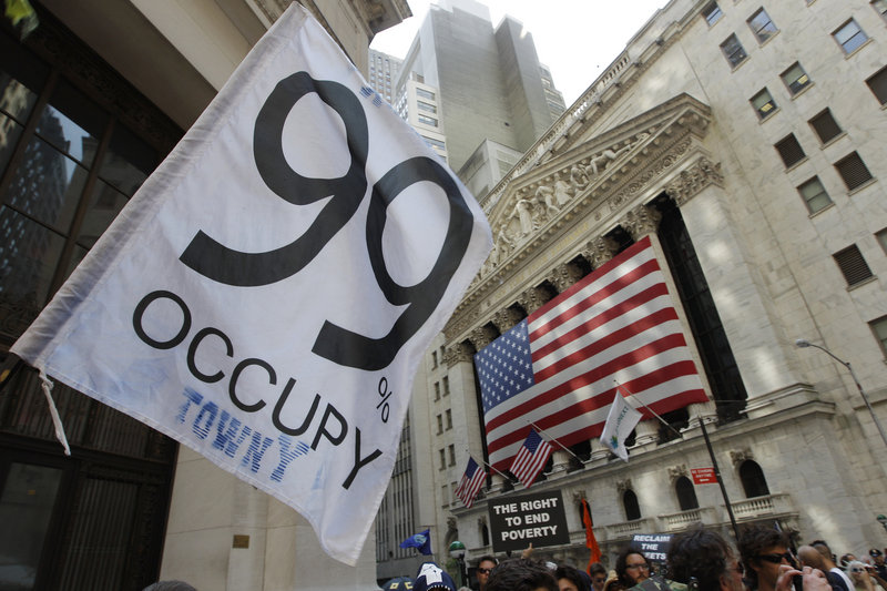 Occupy Wall Street protesters walk past the New York Stock Exchange last July 11. The real threat to “our American way of life” isn’t socialism, but “the concentration of power in a small group of people at the very top of the social pyramid,” like executives who get bonuses when their companies are restructured and many workers laid off, a reader says.