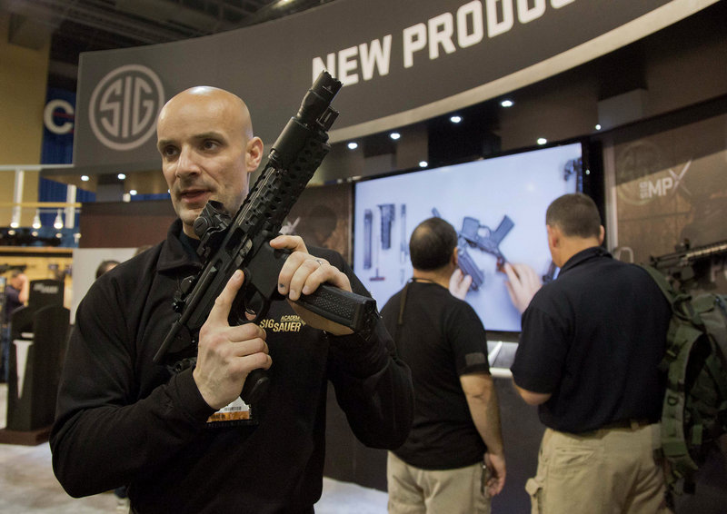 Adam Painchaud, a Sig Sauer representative, demonstrates one of the company’s newest products, the MPX 9mm submachine gun, at the 35th annual SHOT Show on Jan. 15 in Las Vegas. The gun is for military and law enforcement use and not for sale to the public.