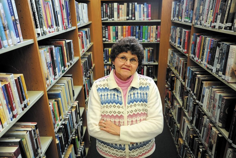 Carol Cooley, a librarian at the Oakland Public Library, stands among some books available for checkout Thursday. Cooley recently called local police about a delinquent book borrower who had failed to return $200 in books.