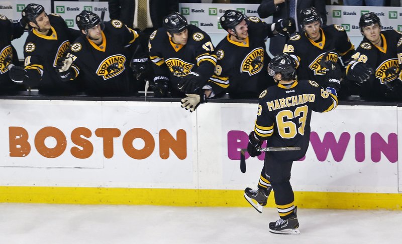 Brad Marchand of the Boston Bruins is welcomed by teammates Tuesday night after scoring a shootout goal that proved the winner against the Devils.