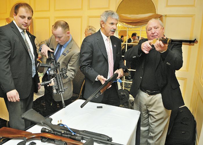 Rep. Matt Pouliot, left, Rep. Corey Wilson and Sen. Roger Katz, all R-Augusta, look over a table of weapons with Richard Beausoleil, far right, of Kennebec County Emergency Management Agency, on Thursday at the Senator Inn and Spa in Augusta.