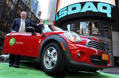FILE - In this April 14, 2011 file photo provided by Zipcar.com, Zipcar Chairman and CEO Scott Griffith stands with a Zipcar Mini-Cooper before the opening bell at the NASDAQ Market Site in New York. Avis is buying Zipcar for $491.2 million, expanding its offerings from traditional car rentals to car sharing services. The boards of both companies unanimously approved the buyout. (AP Photo/Zipcar.com, Craig Ruttle, File)