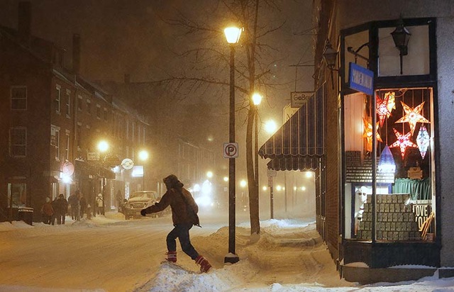 A pedestrian crosses Fore Street, Friday night, Feb. 8, 2013, as the snow continues to fall in Portland.