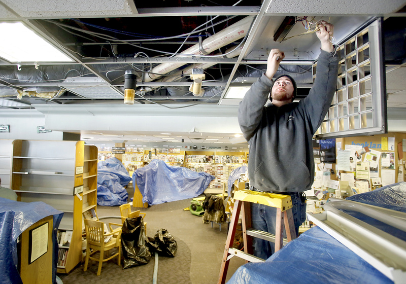 Tony Napolitano of T.A. Napolitano Inc. disconnects lights that were damaged by water after a second-floor sprinkler pipe froze and burst Saturday at Longfellow Books in Portland’s Monument Square.
