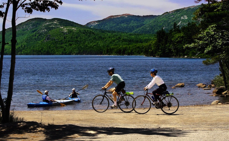 In this June 2005 file photo, bikers cruise along a path while kayakers set off by Eagle Lake in Acadia National Park in Maine. The National Park Service is preparing for large cuts. (AP Photo/Pat Wellenbach)