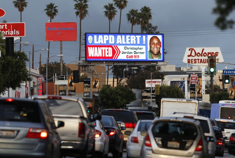 A digital billboard along Santa Monica Boulevard on the west side of Los Angeles shows a "wanted" alert for former Los Angeles police officer Christopher Dorner Friday, Feb. 8, 2013. Dorner is suspected in a spree of violence as part of a vendetta against law enforcement after being fired by the department. He is also a suspect in the shooting deaths of a former LAPD captain's daughter and her fiance, and two other shootings that left an officer dead and two others wounded. (AP Photo/Reed Saxon)