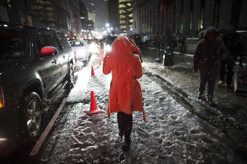 Snow falls on a pedestrian as she leaves the Rag & Bone Fall 2013 fashion collection show during Fashion Week, Friday, Feb. 8, 2013, in New York. Snow began falling across the Northeast on Friday, ushering in what was predicted to be a huge, possibly historic blizzard and sending residents scurrying to stock up on food and gas up their cars. (AP Photo/John Minchillo)