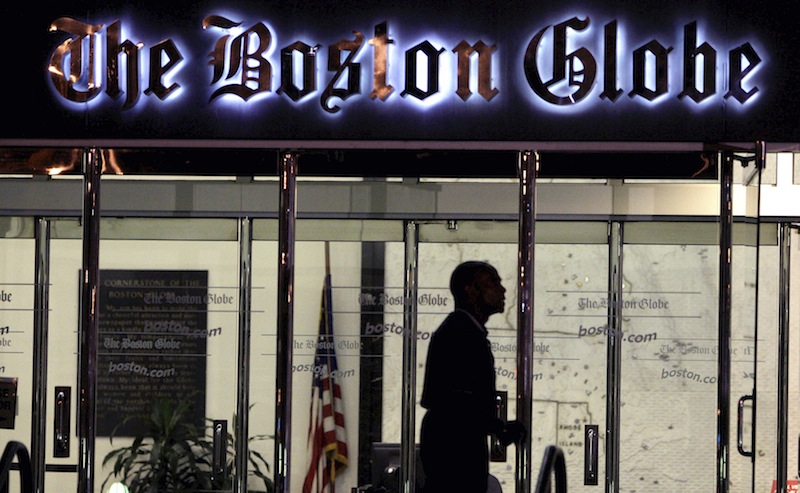 In this July 20, 2009 file photo, a security guard walks past the entrance of The Boston Globe building in the Dorchester neighborhood of Boston. The New York Times Company, which owns The Globe, announced Wednesday, Feb. 20, 2013, that it has put The Globe up for sale. (AP Photo/Charles Krupa)