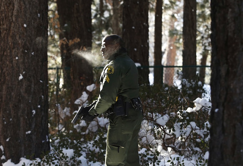 San Bernardino County Sheriff's officer Ken Owens searches a home for former Los Angeles police officer Christopher Dorner in Big Bear Lake, Calif, Sunday, Feb. 10, 2013. The hunt for the former Los Angeles police officer suspected in three killings entered a fourth day in snow-covered mountains Sunday, a day after the police chief ordered a review of the disciplinary case that led to the fugitive's firing and new details emerged of the evidence he left behind. (AP Photo/Jae C. Hong)