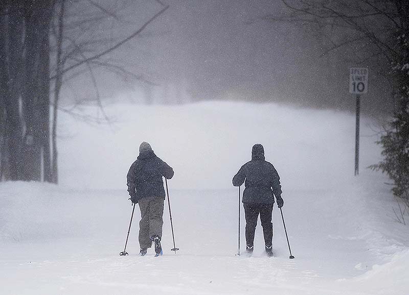 Skiers put fresh tracks on Quarry Road as snow falls in Waterville on Saturday.